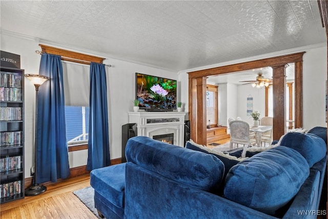 70 Seymour St, Tonawanda-City, NY 14150 - living room featuring wood finished floors, a ceiling fan, a lit fireplace, crown molding, and decorative columns