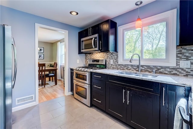 272 Shaftsbury Rd, Brighton, NY 14610 - kitchen featuring stainless steel appliances, a sink, light stone countertops, tasteful backsplash, and dark cabinetry