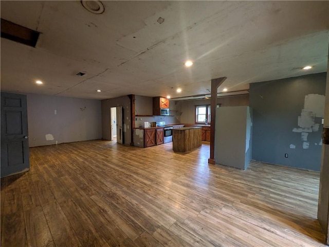 1077 Looker Mtn, Otto Twp, PA 16745 - kitchen with open floor plan, stainless steel electric stove, wood finished floors, brown cabinetry, and a kitchen island