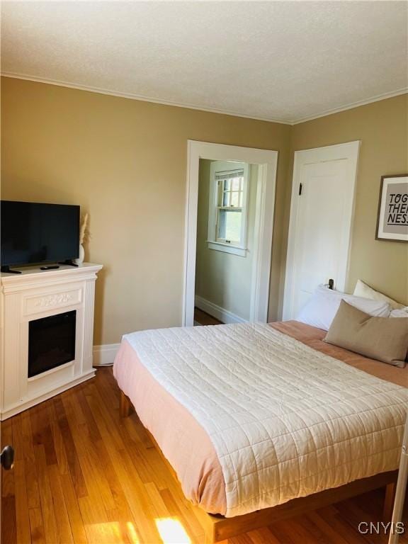 626 Roberts Ave, Syracuse, NY 13207 - bedroom featuring wood finished floors, crown molding, a fireplace, and baseboards