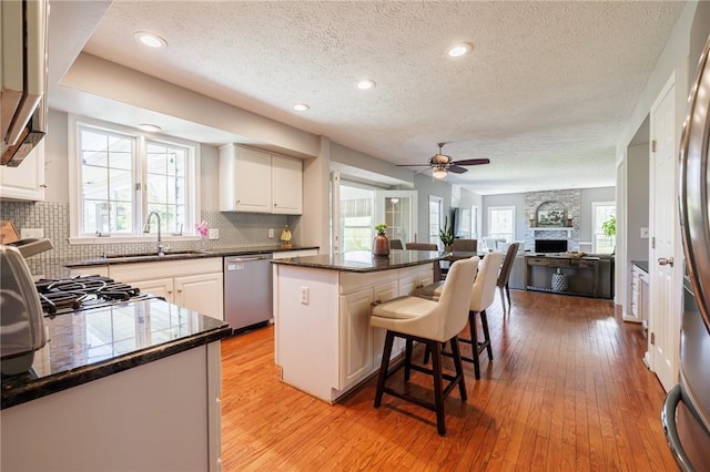 56 Edenfield Rd, Penfield, NY 14526 - kitchen featuring appliances with stainless steel finishes, a sink, a textured ceiling, a center island, and a breakfast bar area