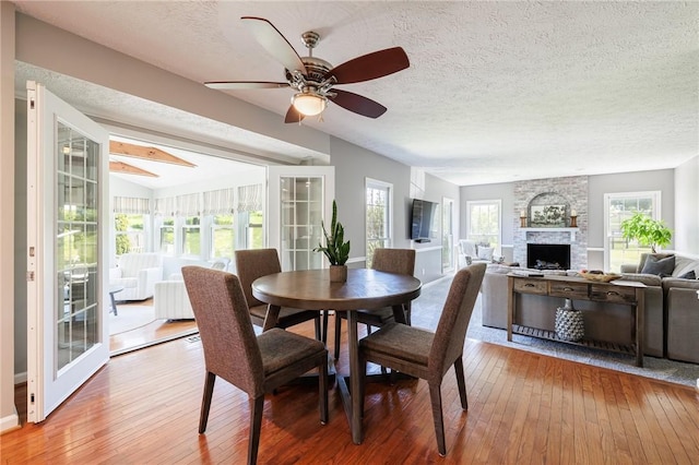 56 Edenfield Rd, Penfield, NY 14526 - dining area with hardwood / wood-style flooring, a ceiling fan, a textured ceiling, and a fireplace