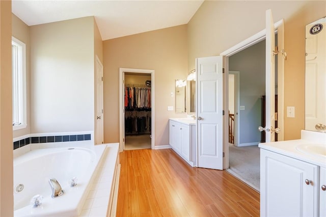 56 Edenfield Rd, Penfield, NY 14526 - full bathroom featuring vanity, a whirlpool tub, wood finished floors, lofted ceiling, and baseboards