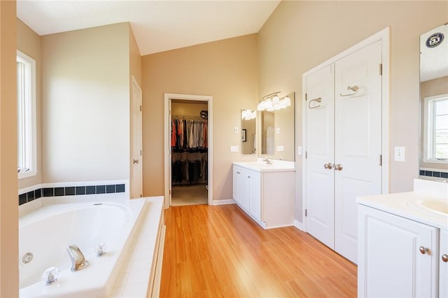 56 Edenfield Rd, Penfield, NY 14526 - bathroom featuring two vanities, a jetted tub, wood finished floors, and lofted ceiling