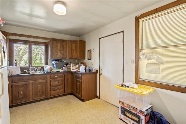 262 Pearl St, Rochester, NY 14607 - kitchen featuring dark countertops, brown cabinets, a sink, light flooring, and freestanding refrigerator