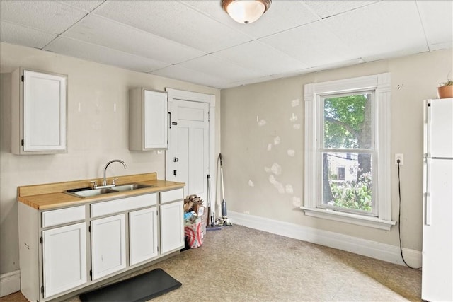 262 Pearl St, Rochester, NY 14607 - kitchen featuring freestanding refrigerator, a sink, a drop ceiling, white cabinetry, and baseboards