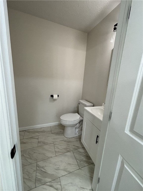 3758 Lake Rd N, Clarkson, NY 14420 - half bathroom with marble look tiles, vanity, toilet, a textured ceiling, and baseboards