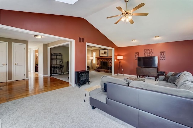 16 Canterbury Trl, Penfield, NY 14450 - carpeted living area with lofted ceiling, a ceiling fan, a wood stove, baseboards, and a brick fireplace