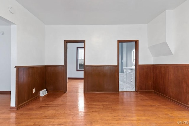 410 John St, Syracuse, NY 13208 - unfurnished room featuring light wood-style floors, wainscoting, and wood walls