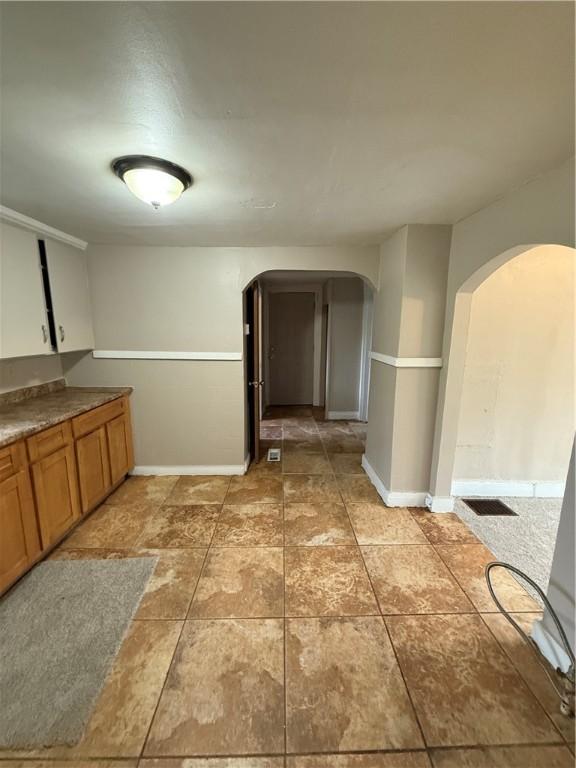 180 Norran Dr, Rochester, NY 14609 - kitchen with arched walkways, baseboards, and brown cabinetry