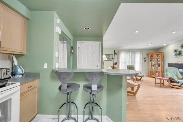 950 Hopkins Rd Unit B, Amherst, NY 14221 - kitchen featuring light brown cabinets, a breakfast bar area, electric range, tasteful backsplash, and light wood-style flooring