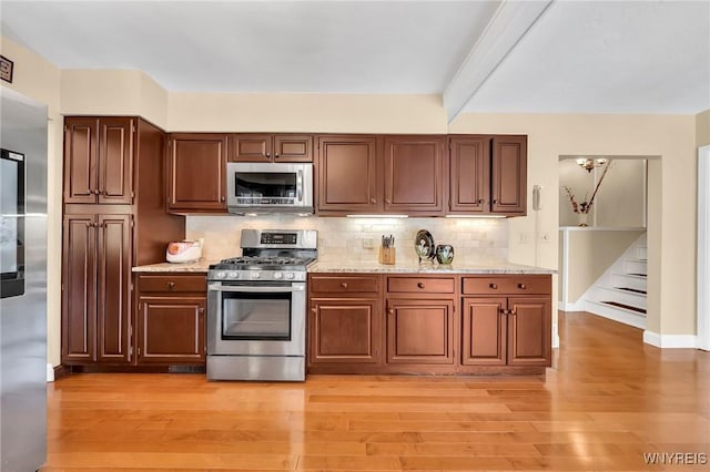 8918 Hurlburt Ln, Clarence, NY 14031 - kitchen featuring stainless steel appliances, light wood-style floors, decorative backsplash, and light stone countertops