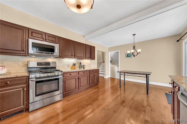 8918 Hurlburt Ln, Clarence, NY 14031 - kitchen featuring appliances with stainless steel finishes, a chandelier, tasteful backsplash, hanging light fixtures, and light wood-style flooring