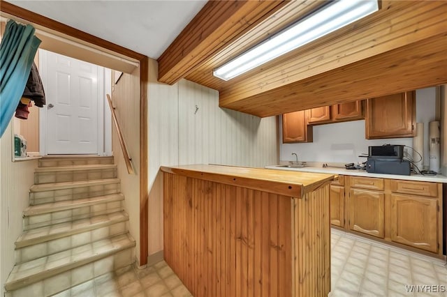 8918 Hurlburt Ln, Clarence, NY 14031 - kitchen featuring light flooring, butcher block counters, a sink, a peninsula, and brown cabinetry