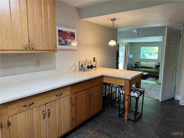 22 Hamilton St, Hamilton, NY 13346 - kitchen featuring a peninsula, light countertops, decorative light fixtures, dark tile patterned floors, and brown cabinets