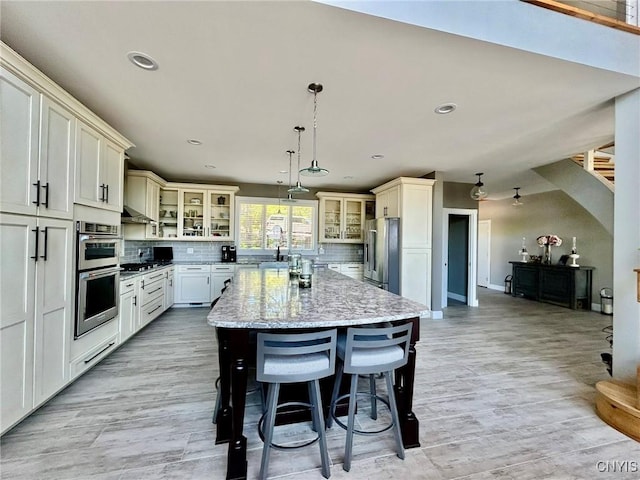 2 Perch Bay Rd, Morristown, NY 13669 - kitchen featuring stainless steel appliances, light stone counters, tasteful backsplash, a kitchen island, and glass insert cabinets