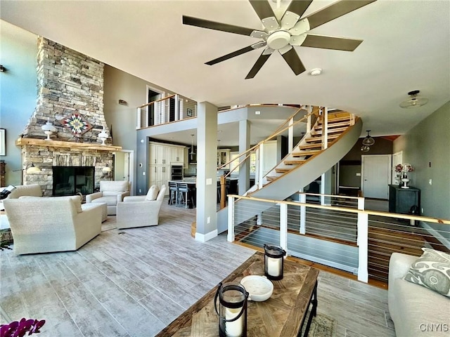 2 Perch Bay Rd, Morristown, NY 13669 - living area featuring ceiling fan, wood finished floors, stairs, a stone fireplace, and baseboards