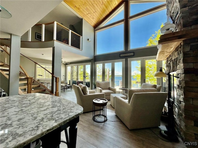 2 Perch Bay Rd, Morristown, NY 13669 - living room featuring a stone fireplace, stairway, high vaulted ceiling, a water view, and wooden ceiling
