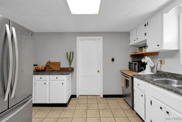 10652 Elm St, North Collins, NY 14111 - kitchen featuring stainless steel appliances, dark countertops, white cabinetry, a drop ceiling, and light tile patterned floors