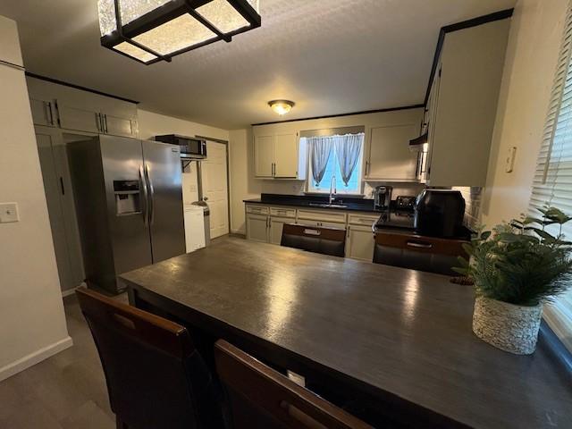 245 Weaver St, Rochester, NY 14621 - kitchen featuring stainless steel appliances, dark countertops, a peninsula, baseboards, and a sink