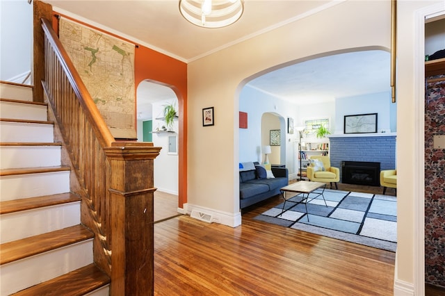 43 Woodland Park, Rochester, NY 14610 - living room featuring wood finished floors, a brick fireplace, stairway, ornamental molding, and arched walkways