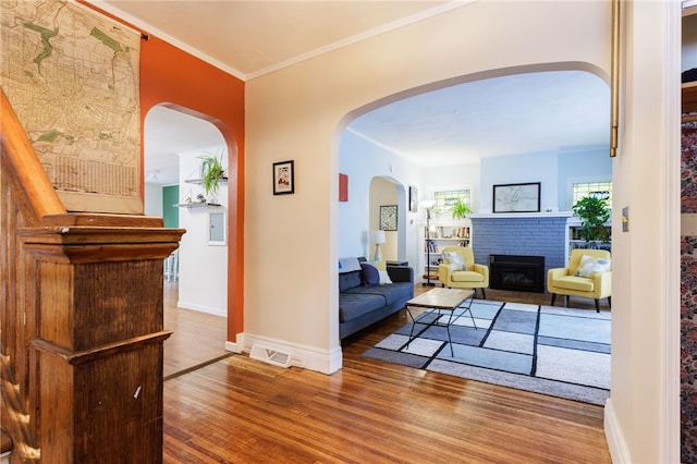 43 Woodland Park, Rochester, NY 14610 - living room featuring wood finished floors, a brick fireplace, crown molding, baseboards, and arched walkways