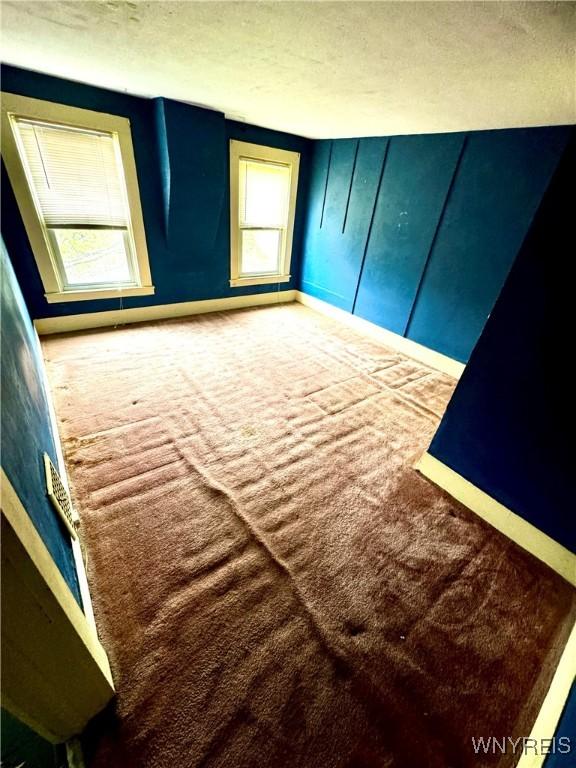 6723 Akron Rd, Lockport Town, NY 14094 - unfurnished bedroom with carpet, a textured ceiling, and baseboards