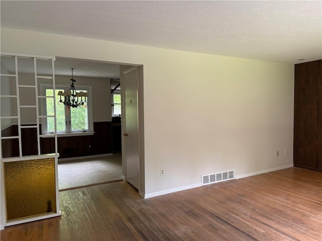 3324 Monroe Wayne County Line Rd, Walworth, NY 14502 - spare room with wood finished floors, a chandelier, a textured ceiling, wood walls, and baseboards