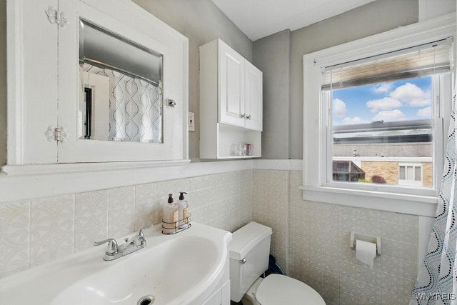 2902 Michigan Ave, Niagara Falls, NY 14305 - bathroom featuring a sink, toilet, healthy amount of natural light, tile walls, and wainscoting