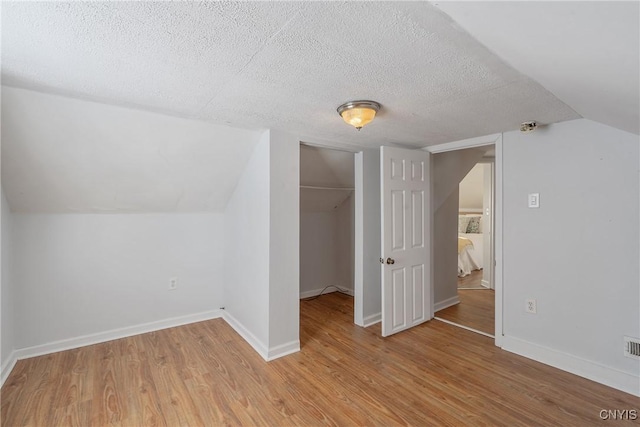 5435 Baldwin St, Cicero, NY 13029 - additional living space featuring light wood-style flooring, vaulted ceiling, a textured ceiling, and baseboards