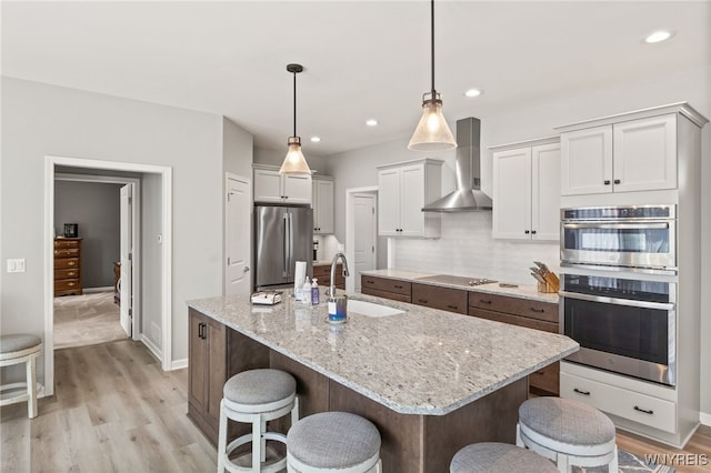 1167 Guinevere Dr, Greece, NY 14626 - kitchen with stainless steel appliances, wall chimney exhaust hood, a sink, a kitchen breakfast bar, and light wood-style flooring