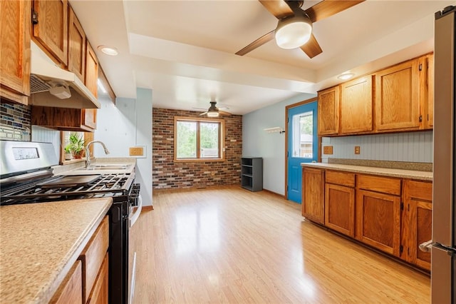 6695 Fisher Rd, Ontario, NY 14589 - kitchen with stainless steel gas stove, ceiling fan, a sink, under cabinet range hood, and light countertops