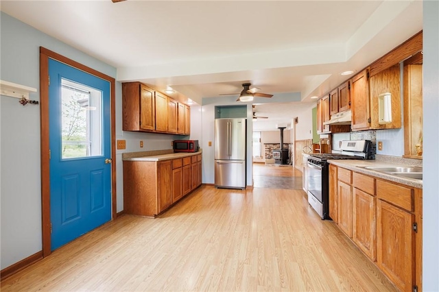 6695 Fisher Rd, Ontario, NY 14589 - kitchen with stainless steel appliances, under cabinet range hood, a wood stove, and light wood-style floors
