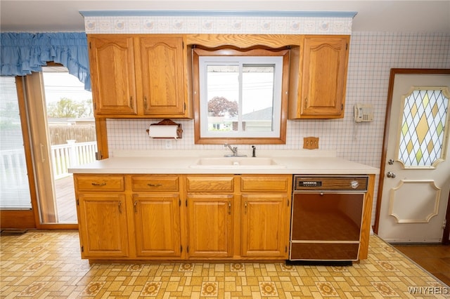 4314 Elmwood Ave, Hamburg, NY 14219 - kitchen with black dishwasher, light countertops, a sink, brown cabinetry, and wallpapered walls