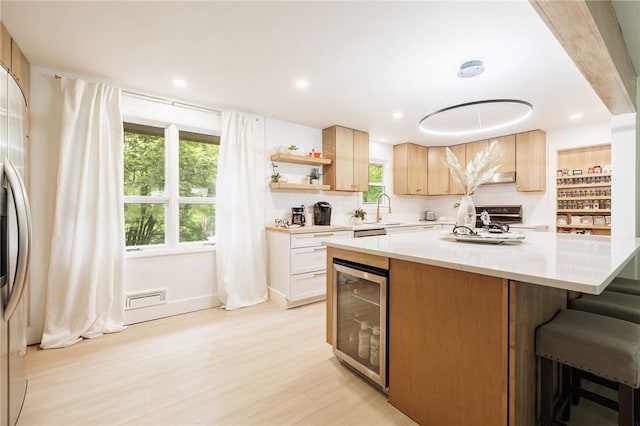 182 Stony Point Trl, Webster, NY 14580 - kitchen featuring beverage cooler, light countertops, a kitchen island, light wood-style flooring, and a sink
