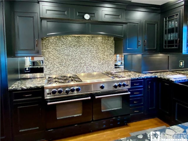 6753 Poverty Hill Rd, Ellicottville, NY 14731 - kitchen with range with two ovens, light stone counters, glass insert cabinets, and decorative backsplash