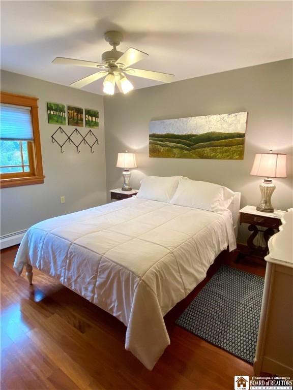 6753 Poverty Hill Rd, Ellicottville, NY 14731 - bedroom with wood finished floors, a ceiling fan, and a baseboard heating unit