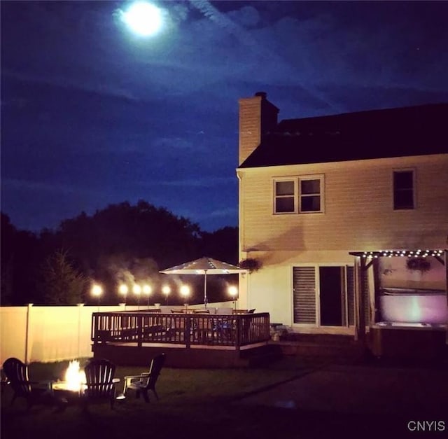 3 Foxwood Dr, Lysander, NY 13027 - back of house at twilight featuring a chimney, a fire pit, a deck, and a covered hot tub