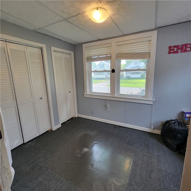 133 California Dr, Greece, NY 14616 - unfurnished bedroom featuring two closets, dark carpet, baseboards, and a drop ceiling