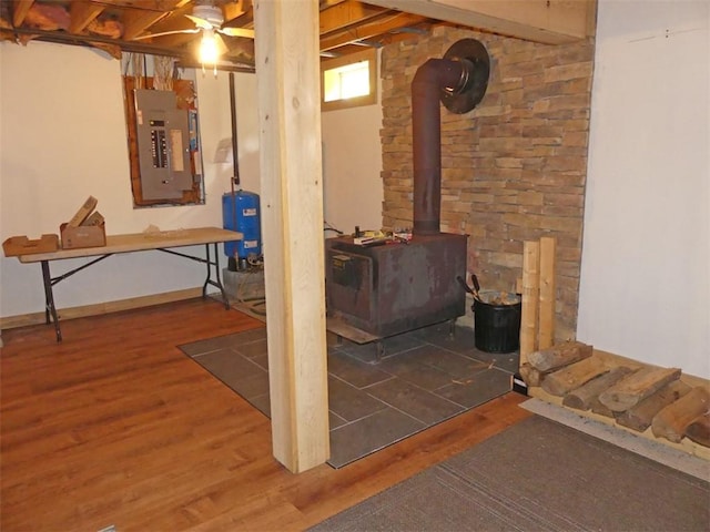 1910 Davis Hollow Rd, Andes, NY 13731 - below grade area with electric panel, a wood stove, wood finished floors, a water pressure tank, and ceiling fan