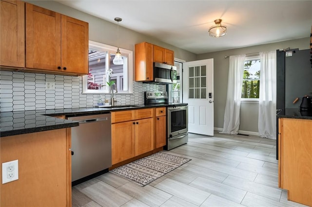 669 Webster Rd, Webster, NY 14580 - kitchen featuring appliances with stainless steel finishes, a sink, decorative backsplash, brown cabinets, and pendant lighting