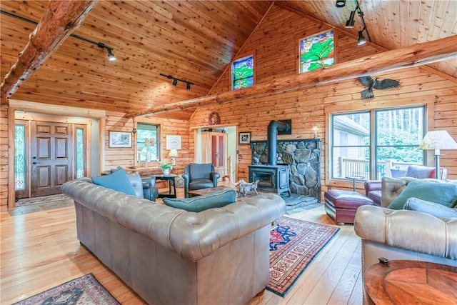 3996 Donley Rd, Italy, NY 14512 - living area with track lighting, wooden ceiling with exposed beams, a wood stove, wooden walls, and light wood finished floors