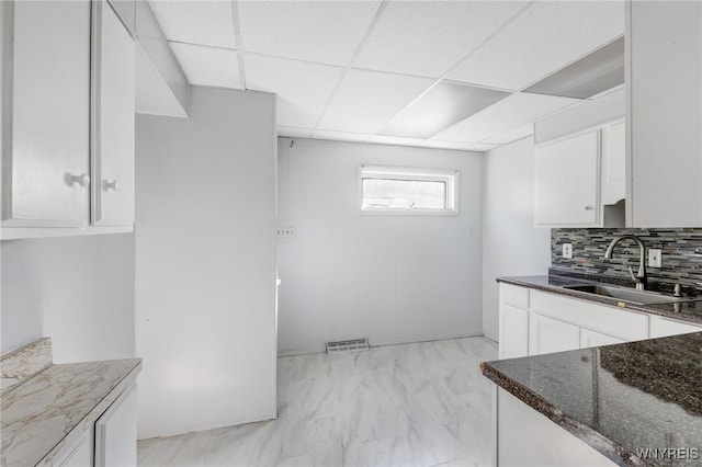46 Wilkes Ave, Buffalo, NY 14215 - kitchen with a sink, dark stone counters, white cabinetry, light marble finish floors, and backsplash