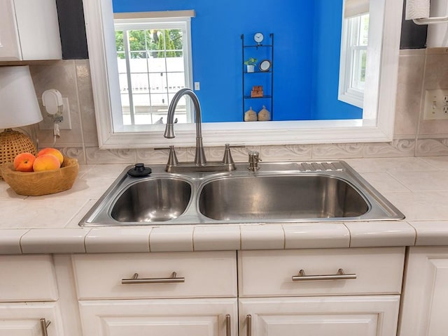 13 W Crest Dr, Gates, NY 14606 - kitchen view of a sink, tile countertops, white cabinetry, and tasteful backsplash