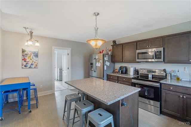 184 Liberty St, Oswego-City, NY 13126 - kitchen featuring stainless steel appliances, dark brown cabinets, a center island, a breakfast bar, and baseboards