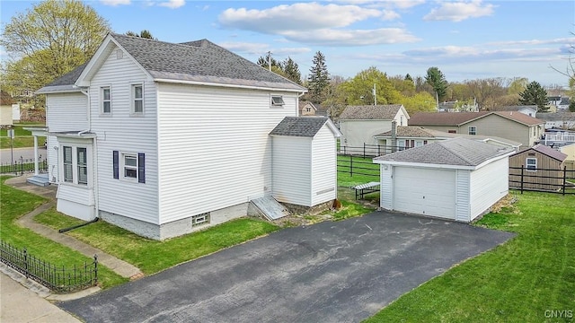 184 Liberty St, Oswego-City, NY 13126 - view of home's exterior featuring an outbuilding, a detached garage, a shingled roof, and asphalt driveway