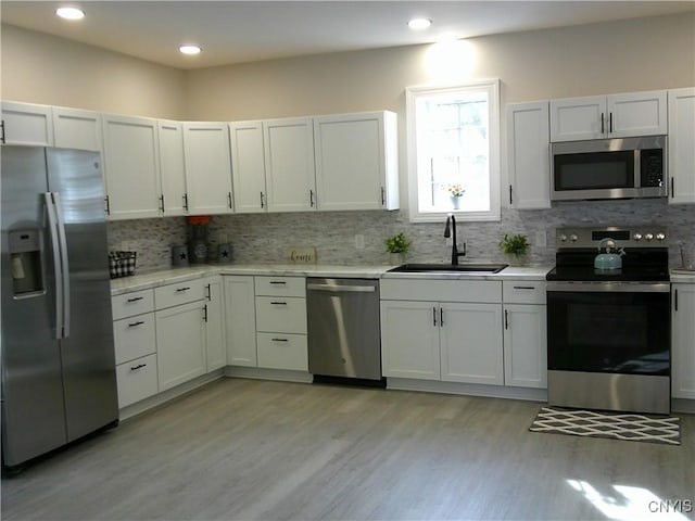 8457 S Main St, Le Ray, NY 13637 - kitchen featuring stainless steel appliances, a sink, decorative backsplash, light wood finished floors, and white cabinets