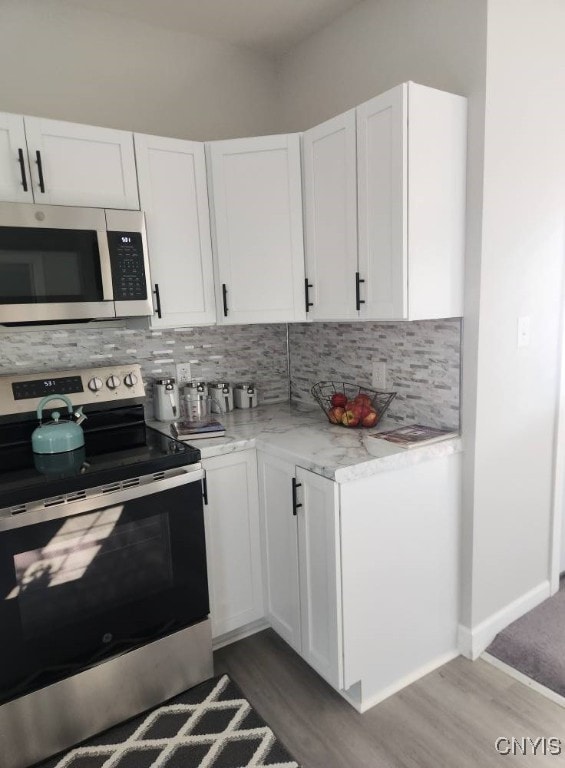 8457 S Main St, Le Ray, NY 13637 - kitchen with stainless steel appliances, wood finished floors, tasteful backsplash, and white cabinetry