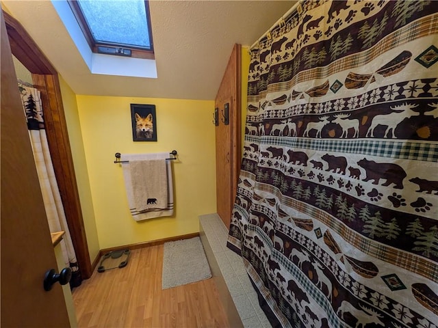 73 Derosia Rd, Lafayette, PA 16738 - bathroom with a skylight, wood finished floors, baseboards, a shower with curtain, and vaulted ceiling