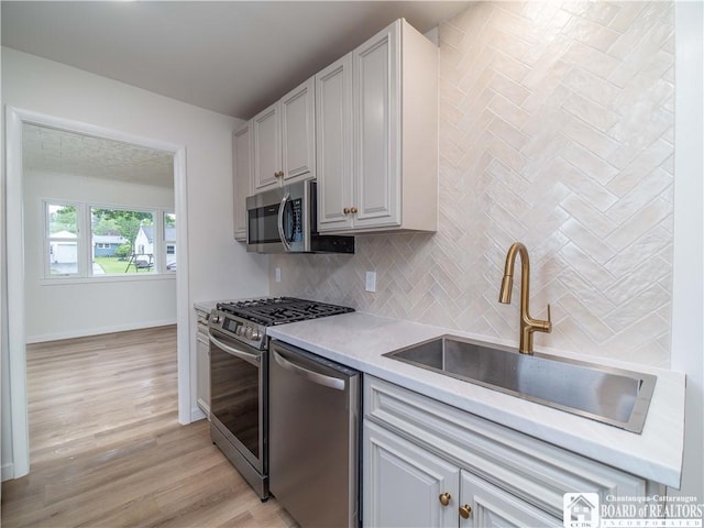 413 Chautauqua Ave, Jamestown, NY 14701 - kitchen with appliances with stainless steel finishes, a sink, backsplash, light countertops, and light wood-style flooring